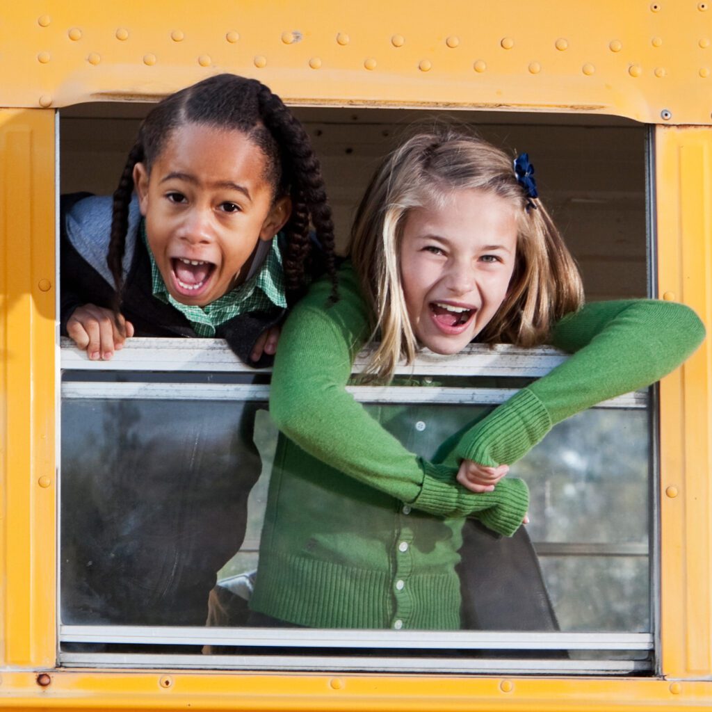 Two children looking out of a school bus window